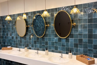 Comptoir noir devant un mur rouge décoré de motifs floraux, éclairé par des suspensions dans un espace à la décoration…