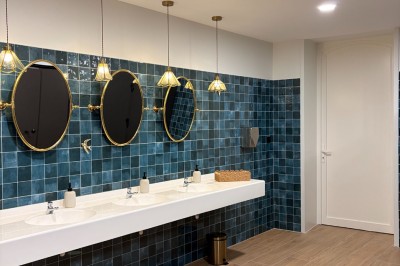 Comptoir noir devant un mur rouge décoré de motifs floraux, éclairé par des suspensions dans un espace à la décoration…