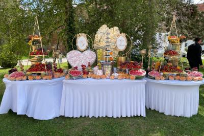 Miniature Banquet extérieur Pièce rustique avec murs en pierre, plafond en bois, réservoir métallique rouge et mobilier simple.