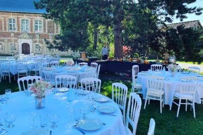 Miniature Brunch en extérieur Pièce rustique avec murs en pierre, plafond en bois, réservoir métallique rouge et mobilier simple.