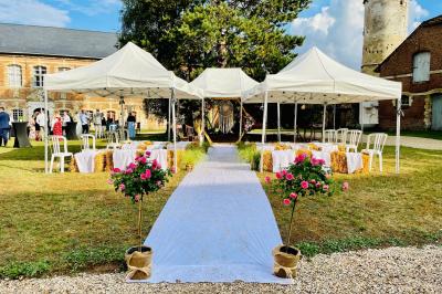 Miniature Cérémonie laïque en extérieur Pièce rustique avec murs en pierre, plafond en bois, réservoir métallique rouge et mobilier simple.