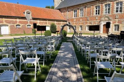 Miniature Cérémonie laïque en extérieur Pièce rustique avec murs en pierre, plafond en bois, réservoir métallique rouge et mobilier simple.