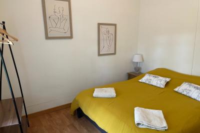 Miniature Chambre lit double Pièce rustique avec murs en pierre, plafond en bois, réservoir métallique rouge et mobilier simple.