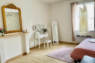 Miniature Chambre nuptiale du gîte Pièce rustique avec murs en pierre, plafond en bois, réservoir métallique rouge et mobilier simple.