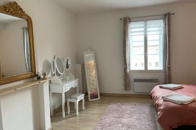 Miniature Chambre nuptiale du gîte Pièce rustique avec murs en pierre, plafond en bois, réservoir métallique rouge et mobilier simple.