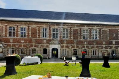 Miniature Cour intérieure du Château Pièce rustique avec murs en pierre, plafond en bois, réservoir métallique rouge et mobilier simple.