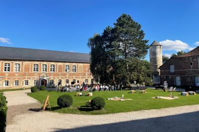 Miniature Cour intérieure du Château Pièce rustique avec murs en pierre, plafond en bois, réservoir métallique rouge et mobilier simple.