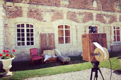 Miniature Décorations Pièce rustique avec murs en pierre, plafond en bois, réservoir métallique rouge et mobilier simple.