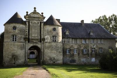 Miniature Façade avant du Château Pièce rustique avec murs en pierre, plafond en bois, réservoir métallique rouge et mobilier simple.