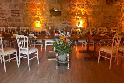 Miniature La Bergerie ( version banquet ) Pièce rustique avec murs en pierre, plafond en bois, réservoir métallique rouge et mobilier simple.