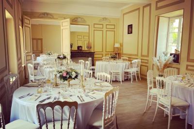 Miniature Les salons de Beaufremez ( version tables rondes ) Pièce rustique avec murs en pierre, plafond en bois, réservoir métallique rouge et mobilier simple.