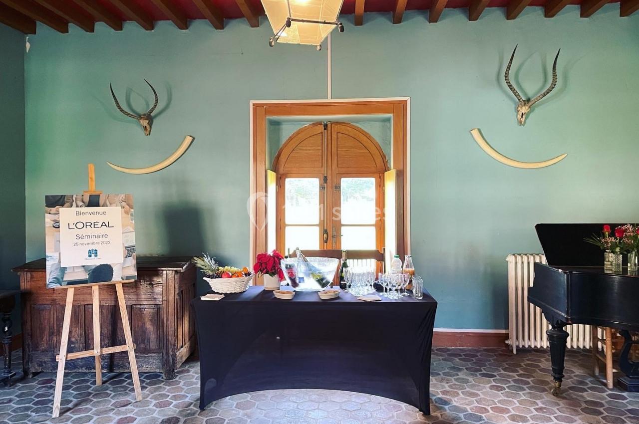 Table dressée avec des collations et boissons dans une salle décorée de bois, trophées muraux et un piano noir.