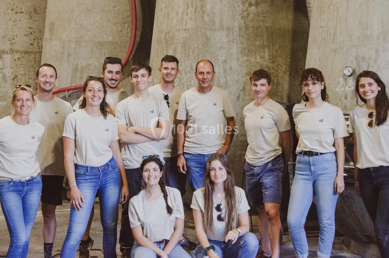 Un groupe de personnes posant devant de grandes cuves en béton dans un environnement industriel.