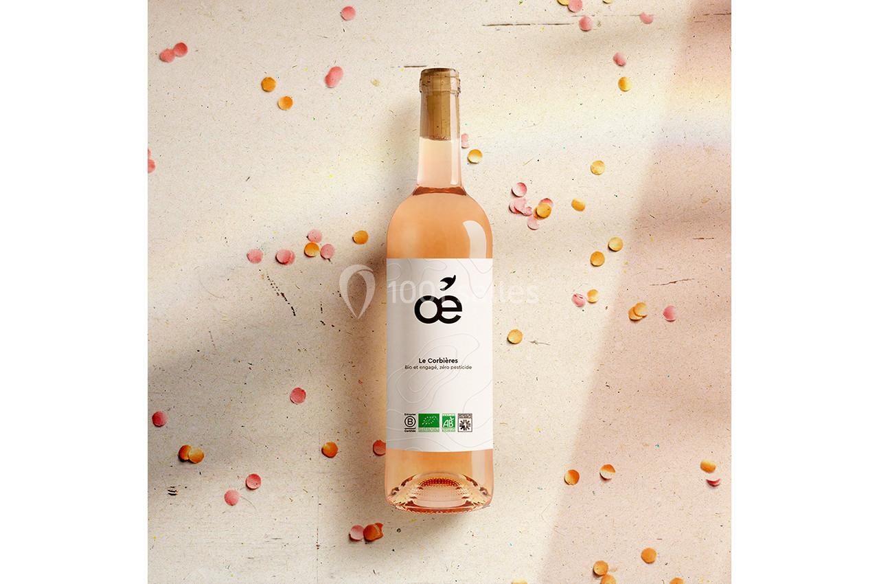 Bouteille de vin rosé posée sur une surface claire, entourée de confettis colorés.