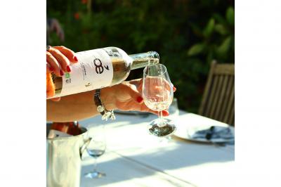 Une bouteille de vin blanc bio, un verre en cours de remplissage, des olives et des herbes sur une table jaune.