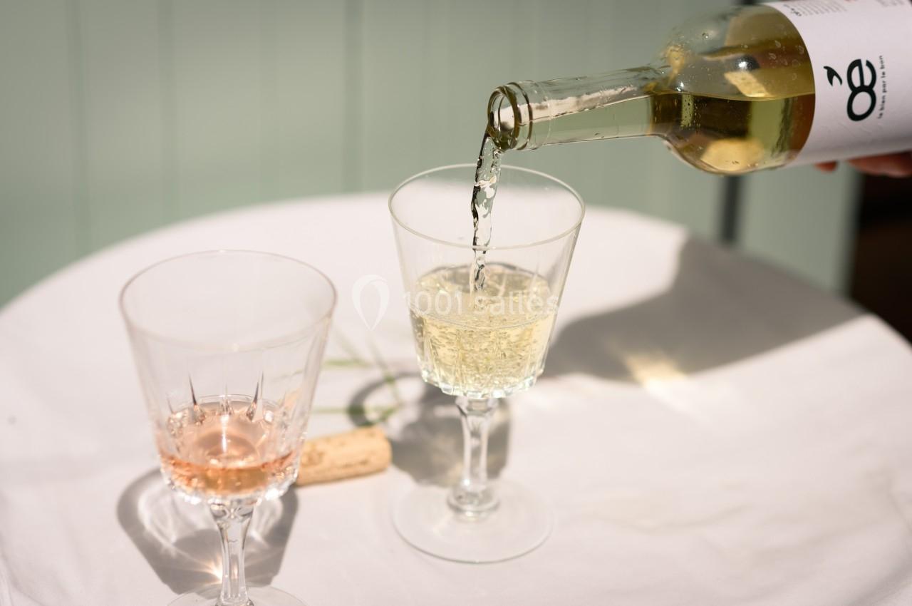 Un verre de vin blanc est servi à côté d'un verre de vin rosé sur une table blanche avec un bouchon en liège.