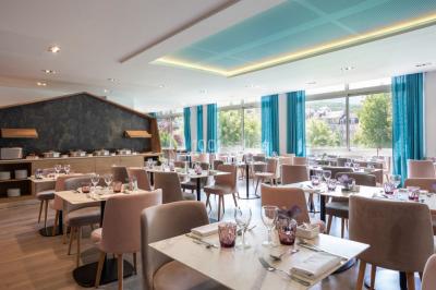 Buffet de petit-déjeuner avec viennoiseries, pain, fruits et fontaine de chocolat dans une salle décorée de motifs tropicaux.