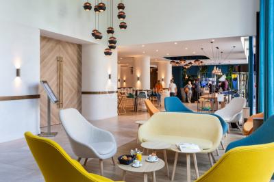 Buffet de petit-déjeuner avec viennoiseries, pain, fruits et fontaine de chocolat dans une salle décorée de motifs tropicaux.