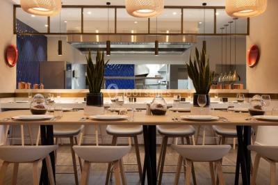 Buffet de petit-déjeuner avec viennoiseries, pain, fruits et fontaine de chocolat dans une salle décorée de motifs tropicaux.