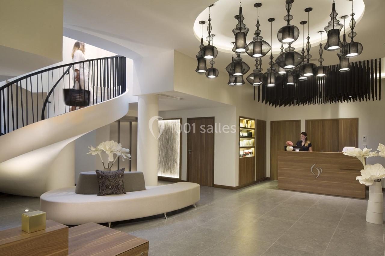 Hall d'accueil moderne avec un comptoir de réception, un escalier en colimaçon et des luminaires suspendus design.