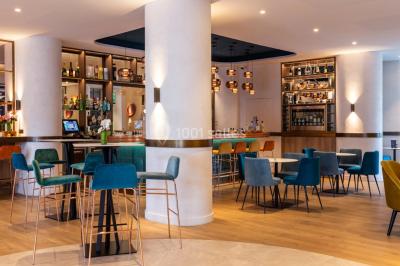 Buffet de petit-déjeuner avec viennoiseries, pain, fruits et fontaine de chocolat dans une salle décorée de motifs tropicaux.