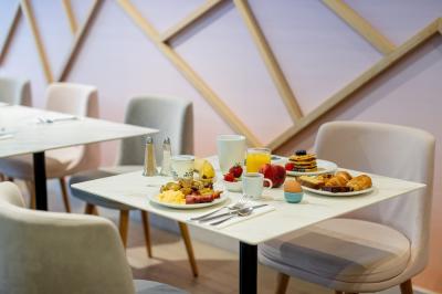 Buffet de petit-déjeuner avec viennoiseries, pain, fruits et fontaine de chocolat dans une salle décorée de motifs tropicaux.