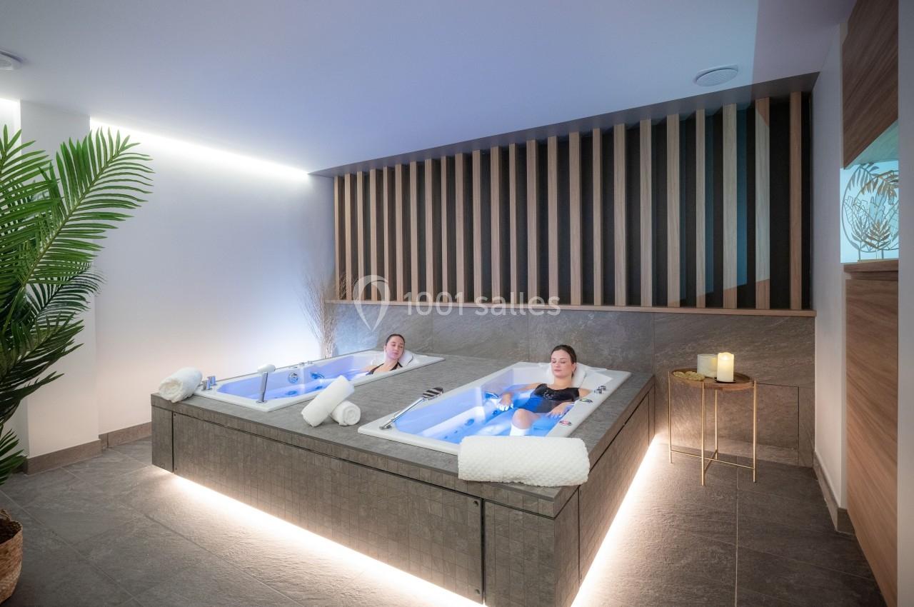 Deux personnes se détendent dans des bains à remous lumineux dans un espace spa moderne et apaisant.