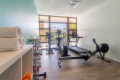 Buffet de petit-déjeuner avec viennoiseries, pain, fruits et fontaine de chocolat dans une salle décorée de motifs tropicaux.