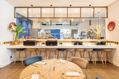 Buffet de petit-déjeuner avec viennoiseries, pain, fruits et fontaine de chocolat dans une salle décorée de motifs tropicaux.