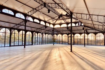 Structure en verre illuminée par des lumières violettes au crépuscule, avec un ciel dégagé en arrière-plan.