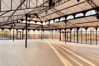 Structure en verre illuminée par des lumières violettes au crépuscule, avec un ciel dégagé en arrière-plan.