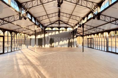 Structure en verre illuminée par des lumières violettes au crépuscule, avec un ciel dégagé en arrière-plan.