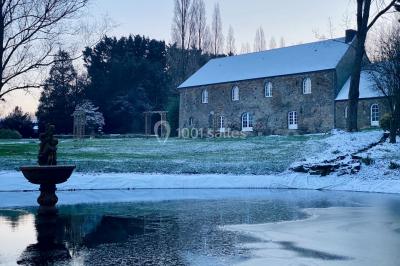 Structure en verre illuminée par des lumières violettes au crépuscule, avec un ciel dégagé en arrière-plan.