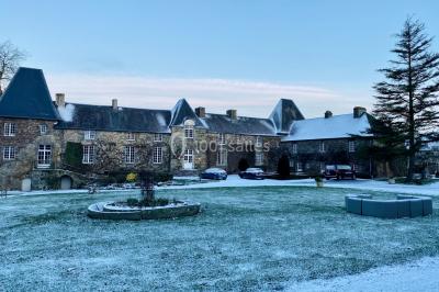 Structure en verre illuminée par des lumières violettes au crépuscule, avec un ciel dégagé en arrière-plan.