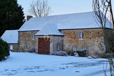 Structure en verre illuminée par des lumières violettes au crépuscule, avec un ciel dégagé en arrière-plan.