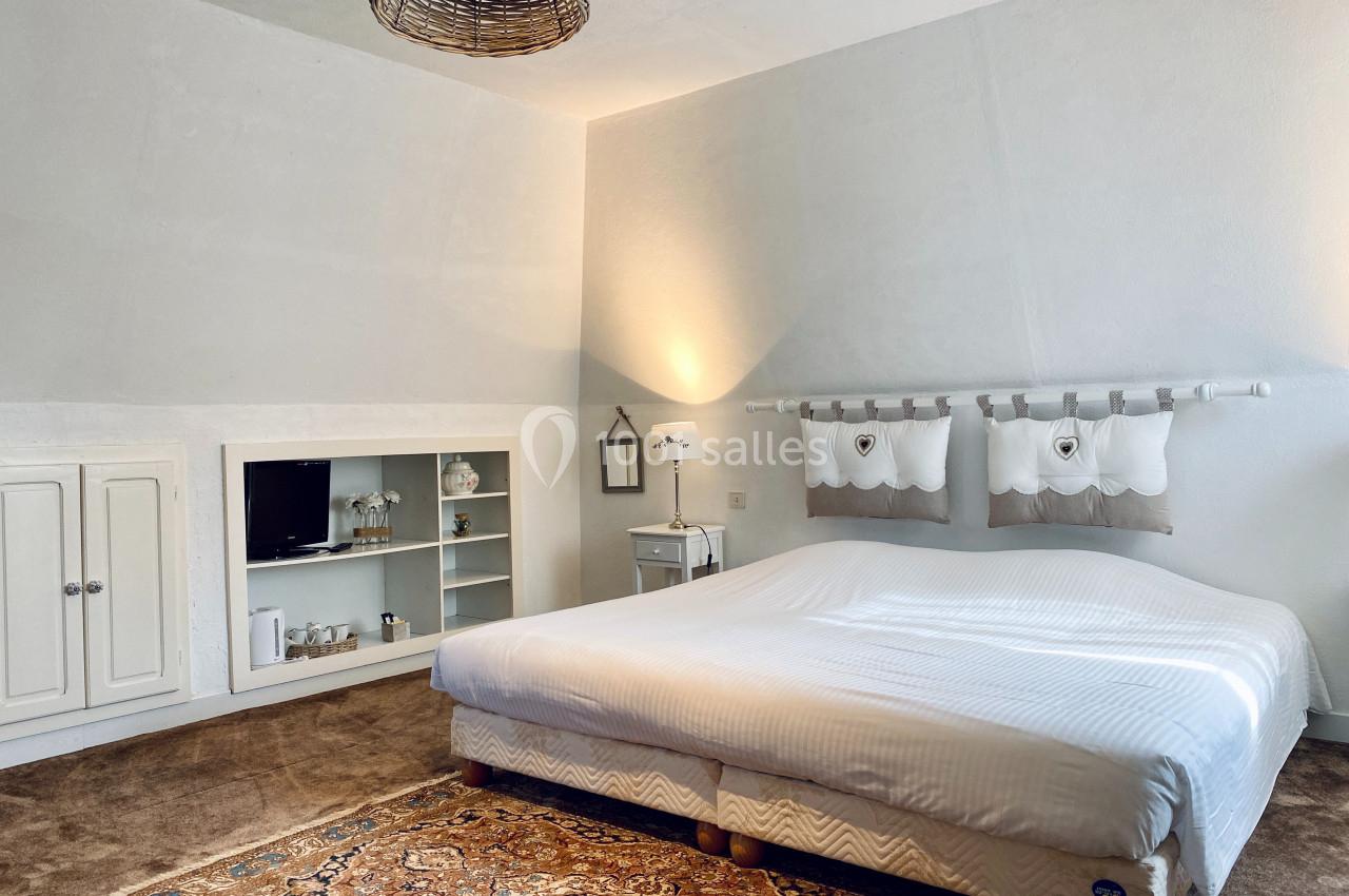 Chambre lumineuse avec lit double, tapis oriental, étagères intégrées et décoration sobre dans des tons neutres.