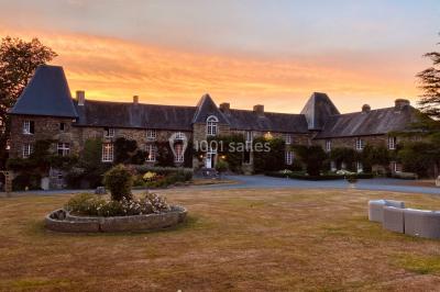 Structure en verre illuminée par des lumières violettes au crépuscule, avec un ciel dégagé en arrière-plan.