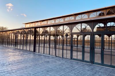 Structure en verre illuminée par des lumières violettes au crépuscule, avec un ciel dégagé en arrière-plan.