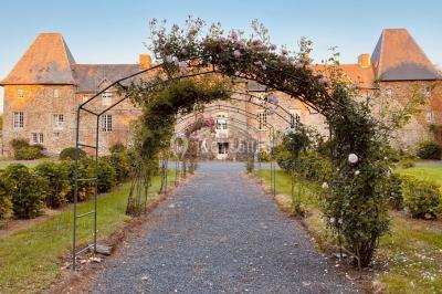 Structure en verre illuminée par des lumières violettes au crépuscule, avec un ciel dégagé en arrière-plan.