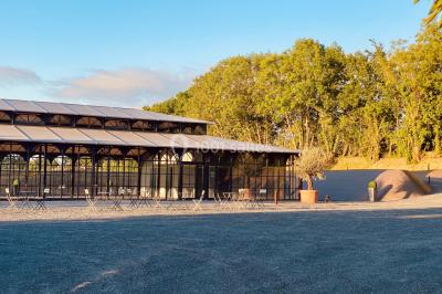 Structure en verre illuminée par des lumières violettes au crépuscule, avec un ciel dégagé en arrière-plan.
