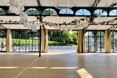 Structure en verre illuminée par des lumières violettes au crépuscule, avec un ciel dégagé en arrière-plan.