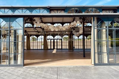 Structure en verre illuminée par des lumières violettes au crépuscule, avec un ciel dégagé en arrière-plan.