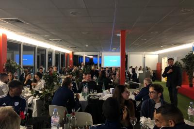 Centre de table avec bougies torsadées, fleurs colorées et nappe orange, entouré de verres et couverts.