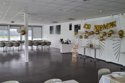 Centre de table avec bougies torsadées, fleurs colorées et nappe orange, entouré de verres et couverts.