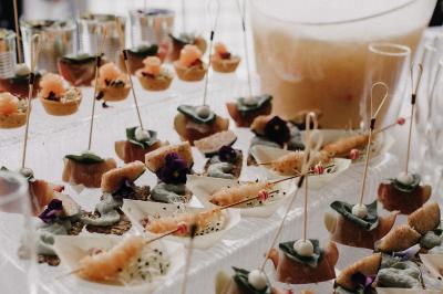 Centre de table avec bougies torsadées, fleurs colorées et nappe orange, entouré de verres et couverts.