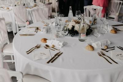 Centre de table avec bougies torsadées, fleurs colorées et nappe orange, entouré de verres et couverts.