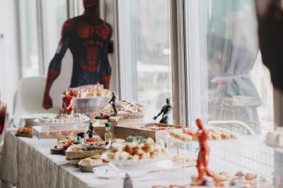 Centre de table avec bougies torsadées, fleurs colorées et nappe orange, entouré de verres et couverts.
