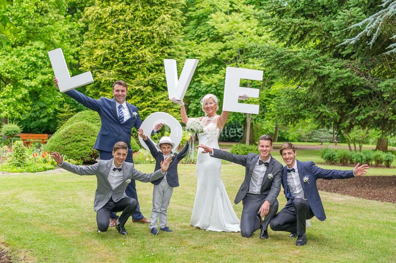 Un groupe de personnes posant dans un jardin, tenant des lettres formant le mot ’LOVE’.