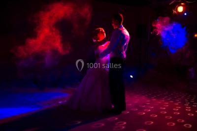Un couple danse sous des lumières colorées dans une ambiance tamisée.