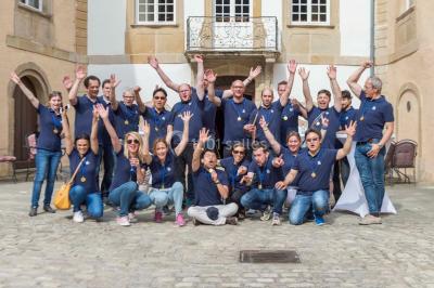 Un groupe de personnes en tenue formelle pose sur une scène lors d'un événement avec un écran affichant des logos en arrière…